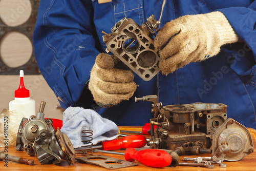 Mechanic repairing the old car engine carburetor