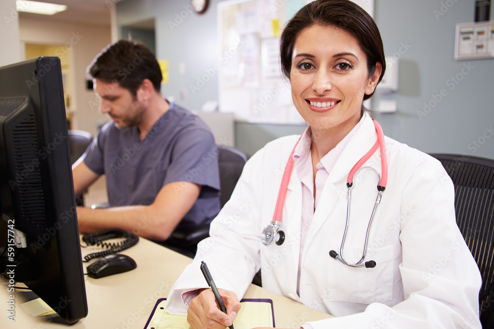 Female Doctor With Male Nurse Working At Nurses Station Female Doctor With Male Nurse Working At Nurses Station