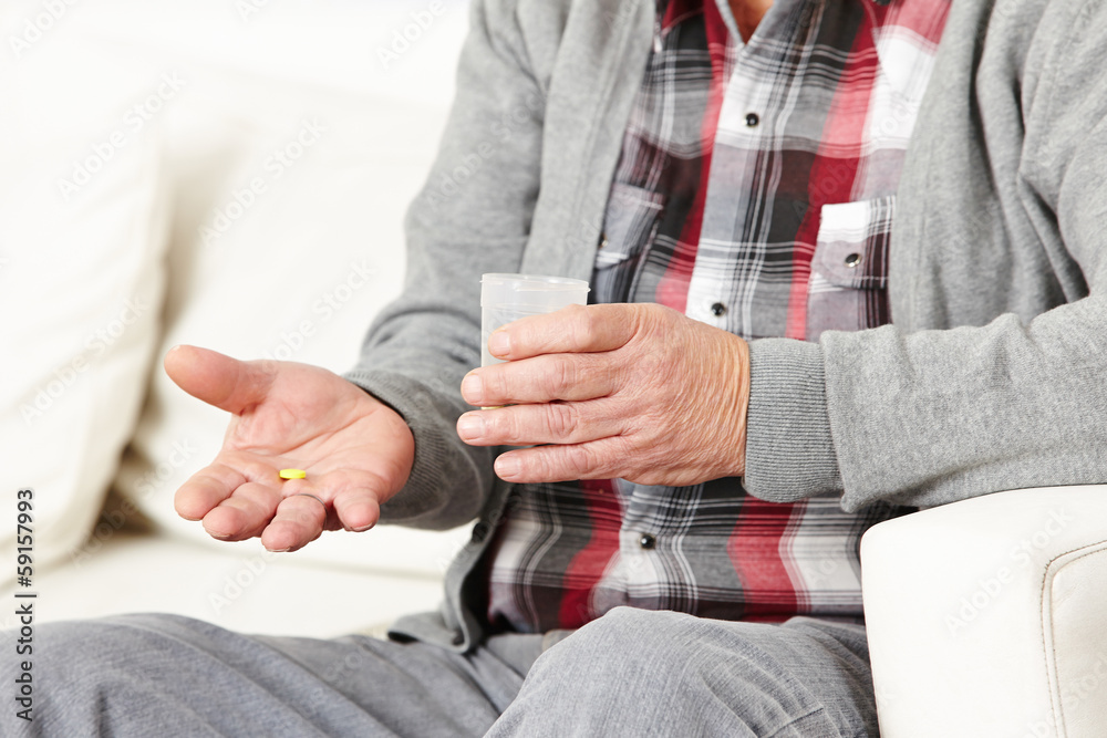 Old man taking pills with water