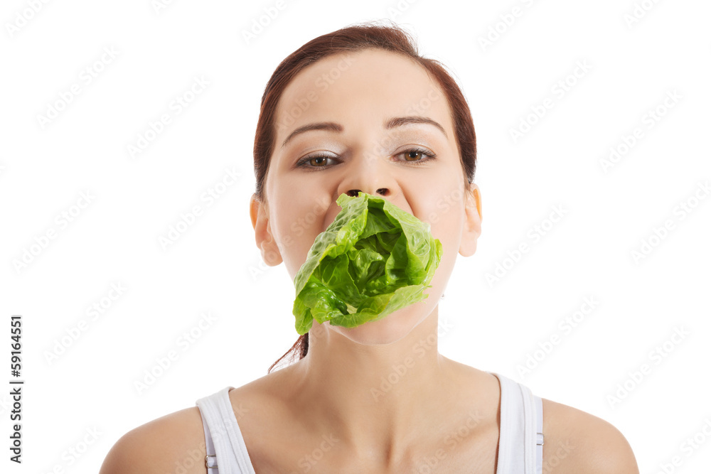 Beautiful woman with leaf of lettuce in mouth.