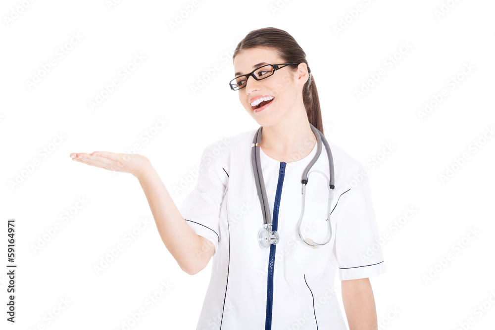 Young beautiful female doctor showing on copy space. Young beautiful female doctor showing on copy space.