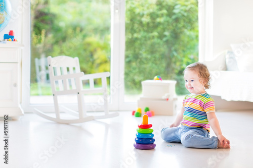 Adorable toddler girl playing with a colorful pyramis in a beaut