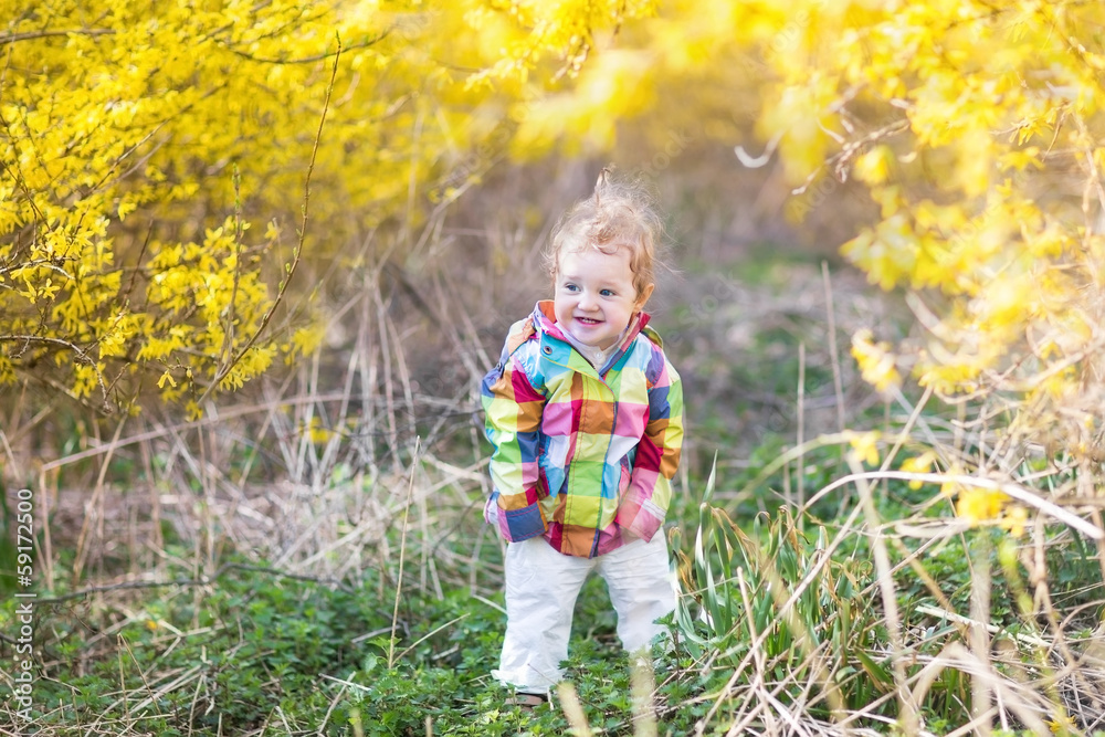 Adorable baby girl playing in a sunny park under a yellow tree