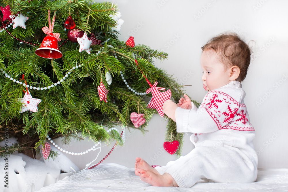 Sweet funny baby girl playing with Christmas tree decoration