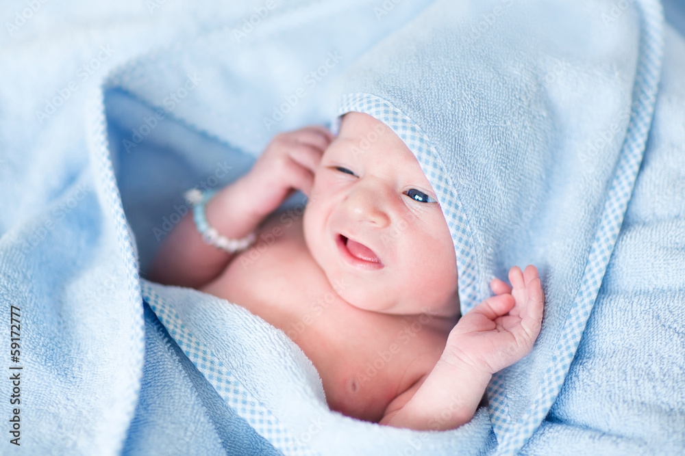 Funny newborn baby covered n a blue bath towel Funny newborn baby covered n a blue bath towel