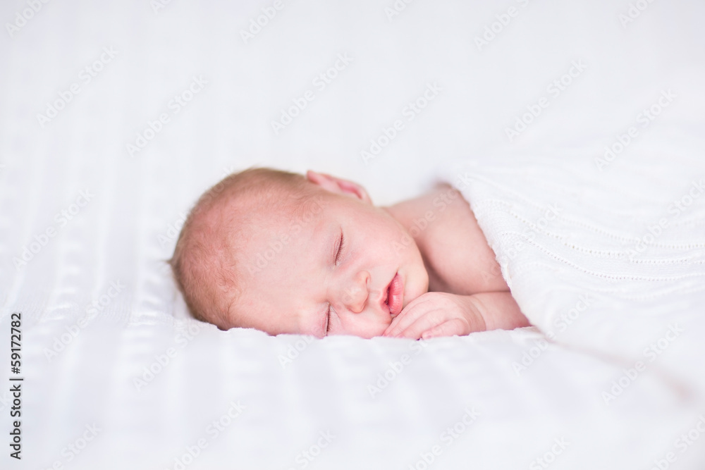 Adorable newborn baby sleeping under a knitted blanket Adorable newborn baby sleeping under a knitted blanket