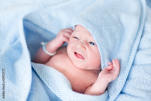 Funny newborn baby covered n a blue bath towel