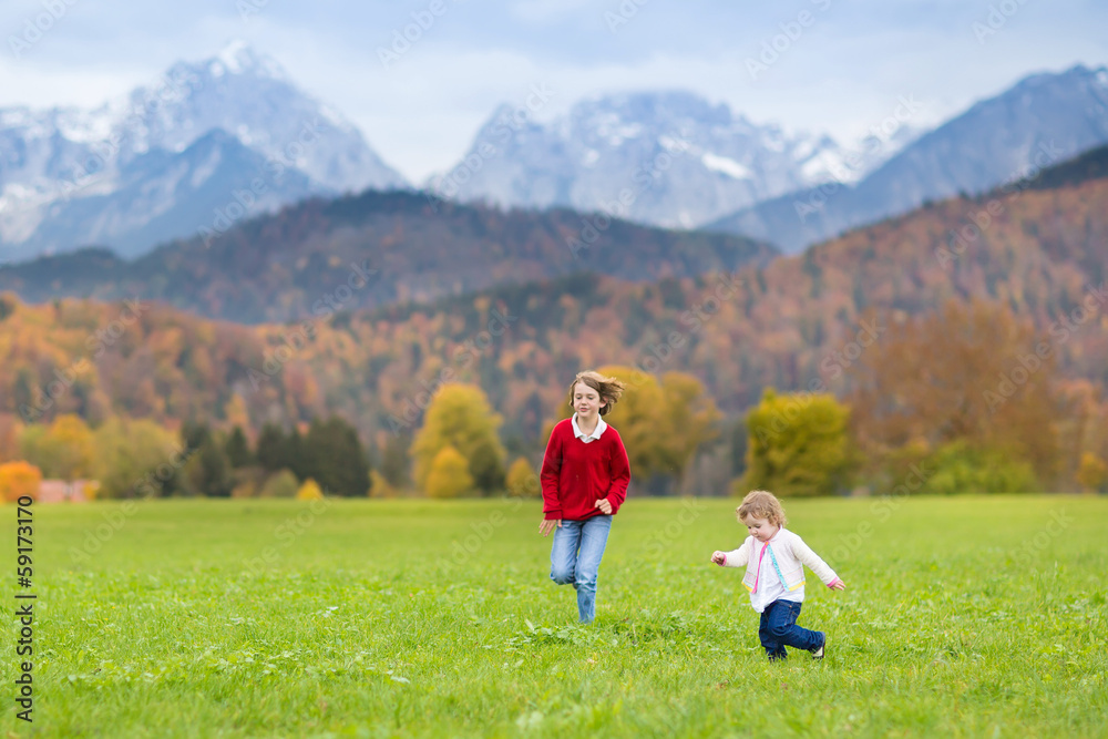 Baby girl and her teenager brother running in the field