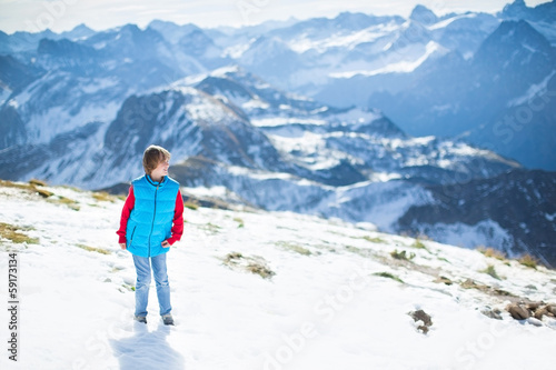 Happy boy playing in snow on top of a beautiful mountain