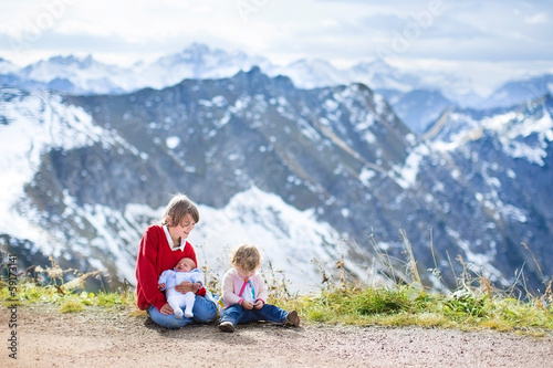 A teenager boy, toddler girl and newborn baby in mountains