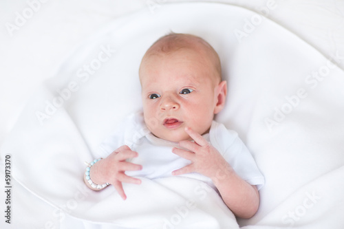Adorable newborn baby relaxing on a white blanket