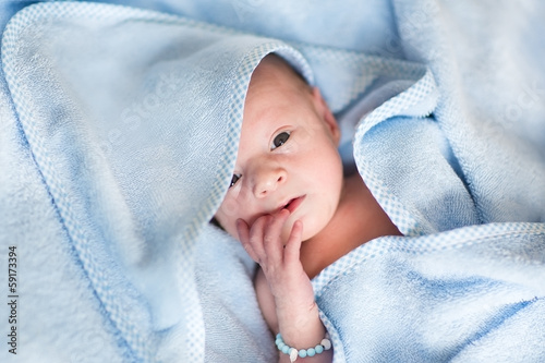 Newborn baby relaxing after a bath in a blue towel