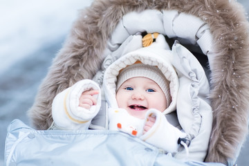 Happy laughing baby girl enjoying a walk in a snowy winter parl