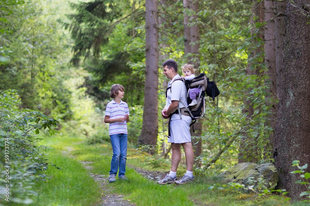 Young father hiking with his school age son and baby daughter