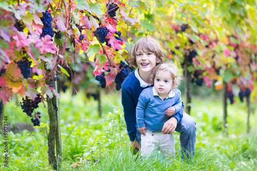 Cute laughing brother and baby sister playing in a vineyard