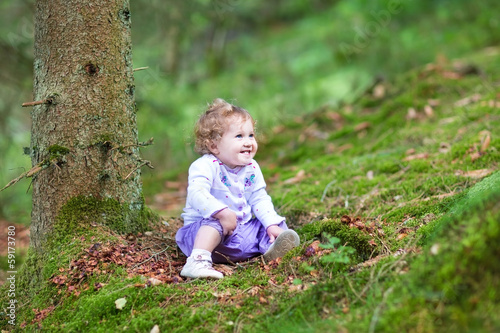Happy laughing baby girl playing in a beautiful pine wood forest