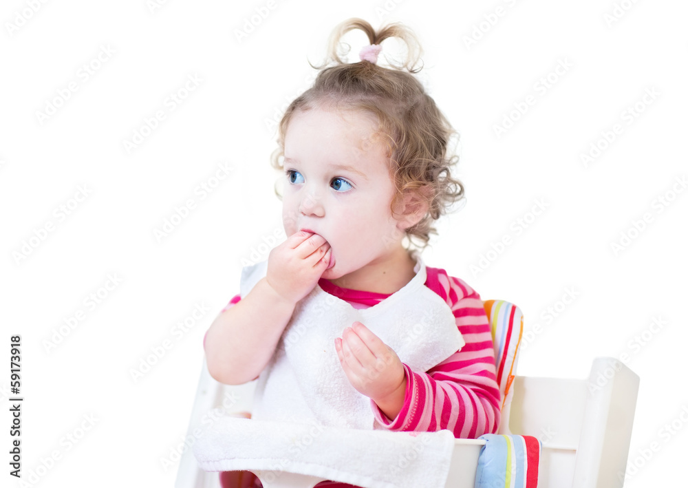 Funny baby girl eating lunch in a white high chair Funny baby girl eating lunch in a white high chair
