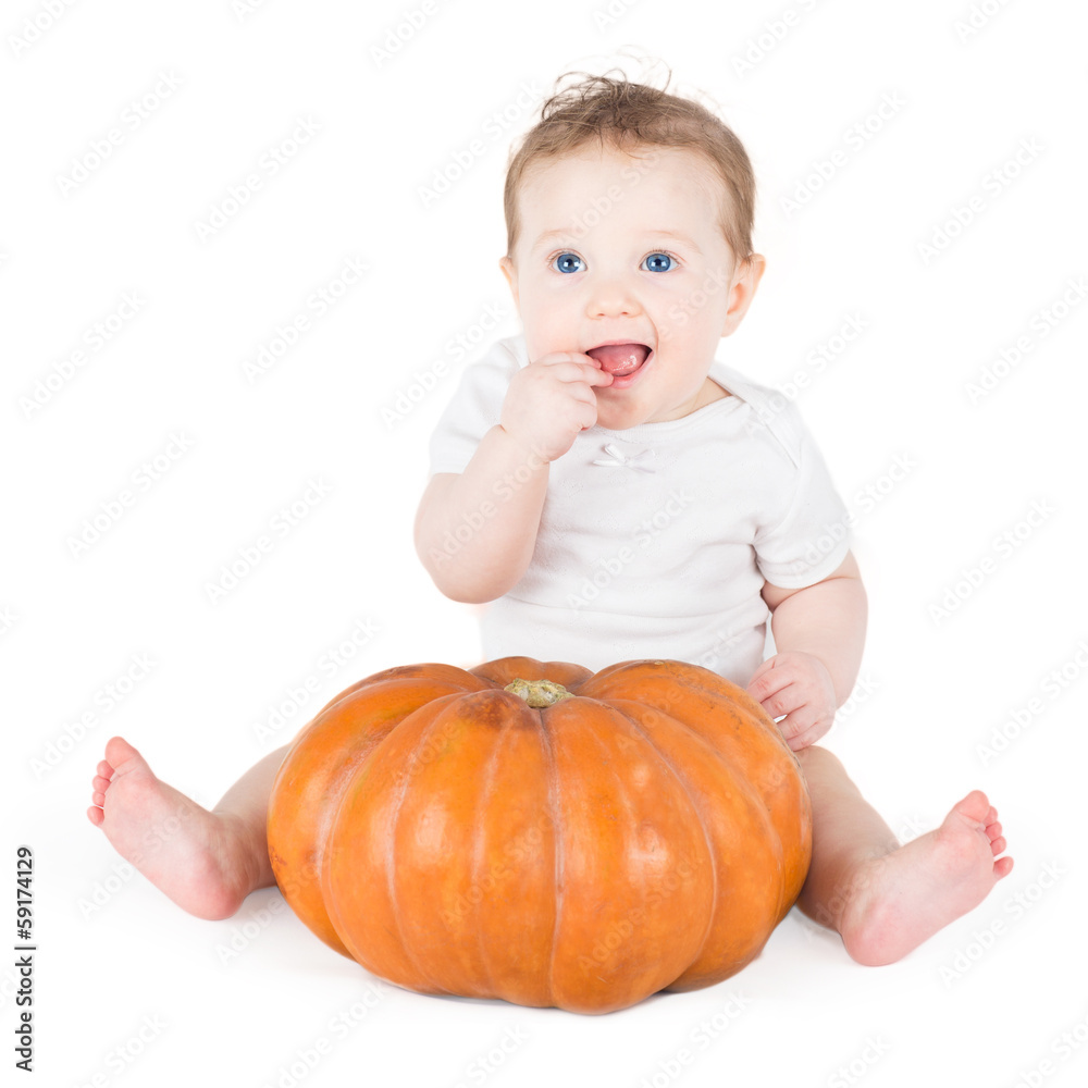 Funny baby girl playing with a huge pumpkin on white background Funny baby girl playing with a huge pumpkin on white background