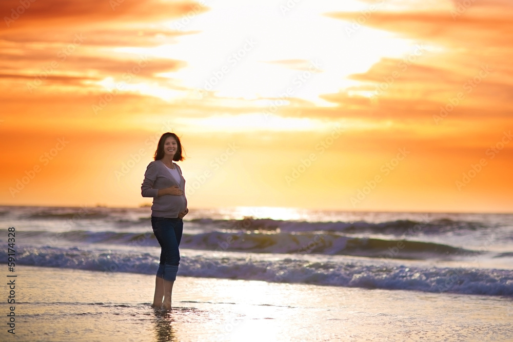 Silhouette of a young pregnant woman with a sunset at a beach