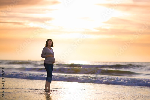 Silhouette of a young pregnant woman with a sunset at a beach © famveldman
