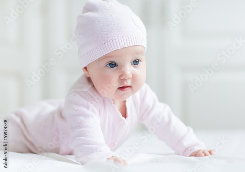 Beautiful baby girl with big blue eyes on a white blanket