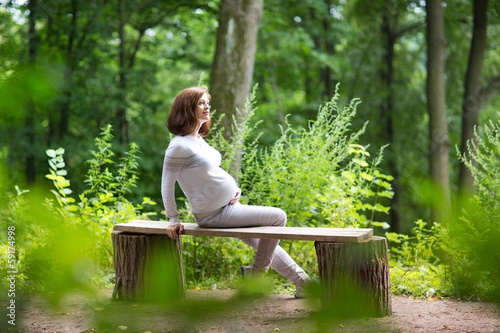 Young pregnant woman relaxing in the park after an active walk