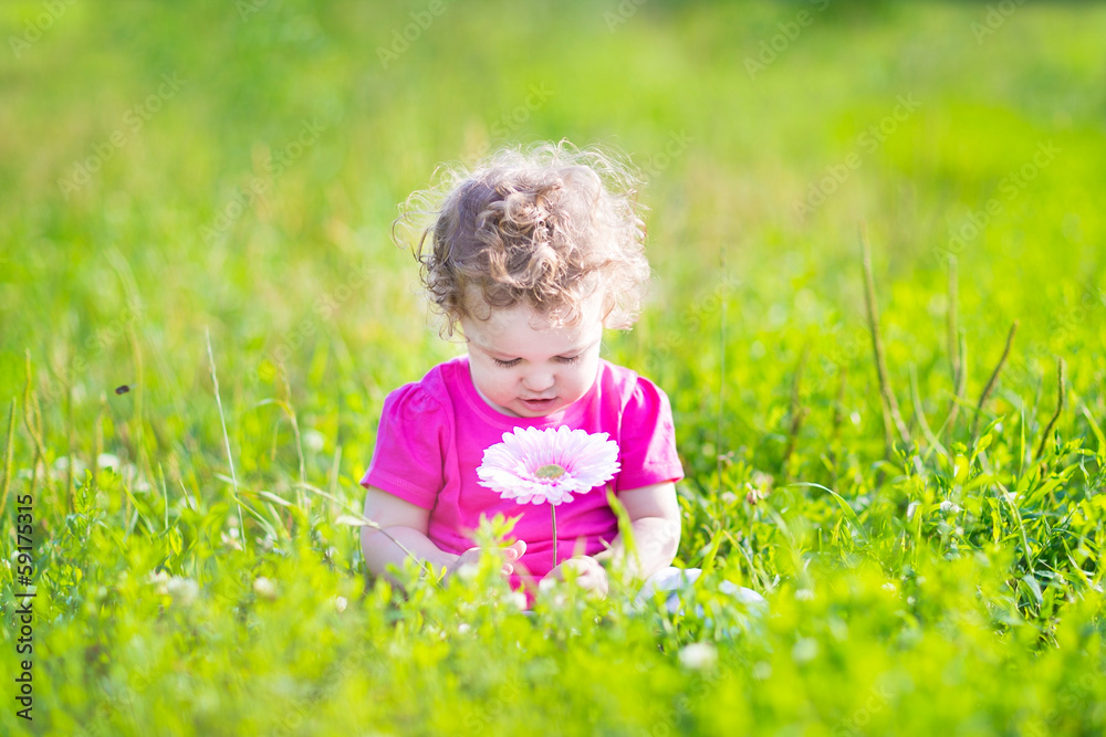 Little girl playing with a big pink flower in the garden Little girl playing with a big pink flower in the garden