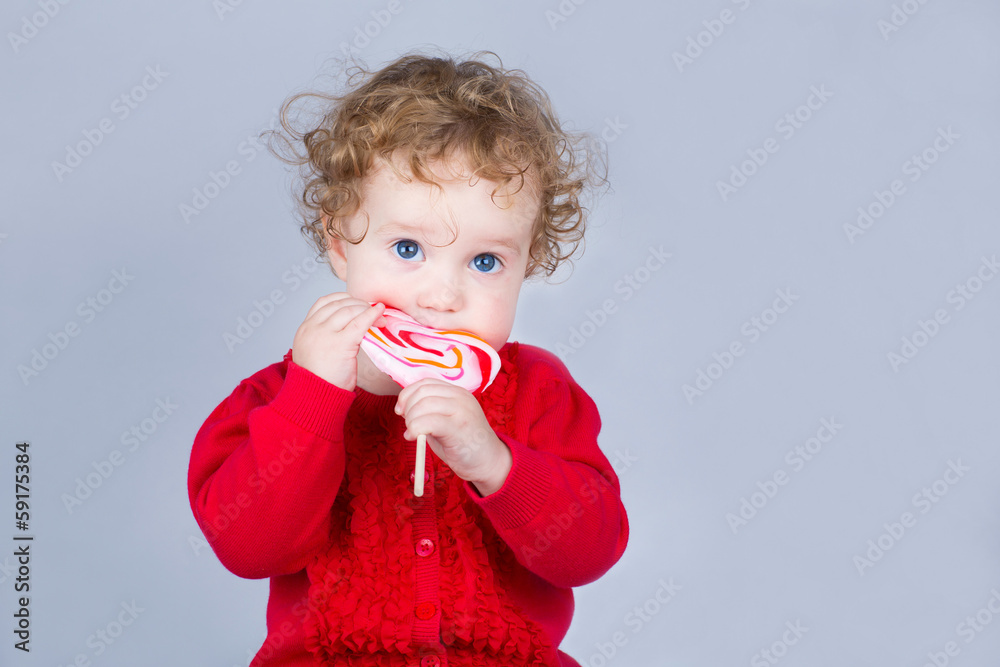 Cute baby girl with a heart shaped candy - obrazy, fototapety, plakaty 