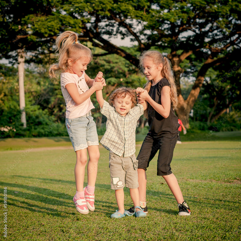 three happy little kids playing in the park in the day time three happy little kids playing in the park in the day time