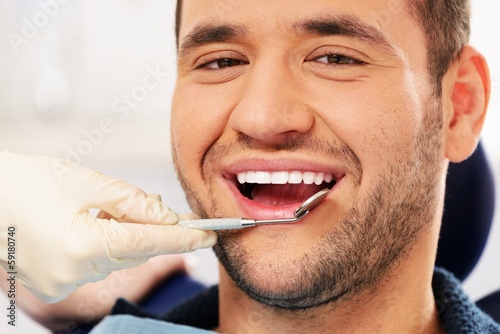 Happy man doing teeth checkup at dentist's surgery