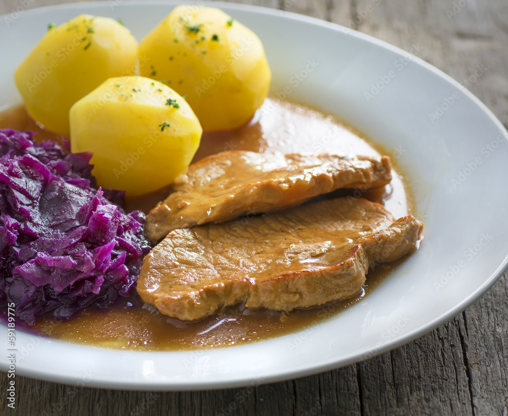 Schweinebraten mit Petersilienkartoffeln und Rotkohl Stock Photo ...