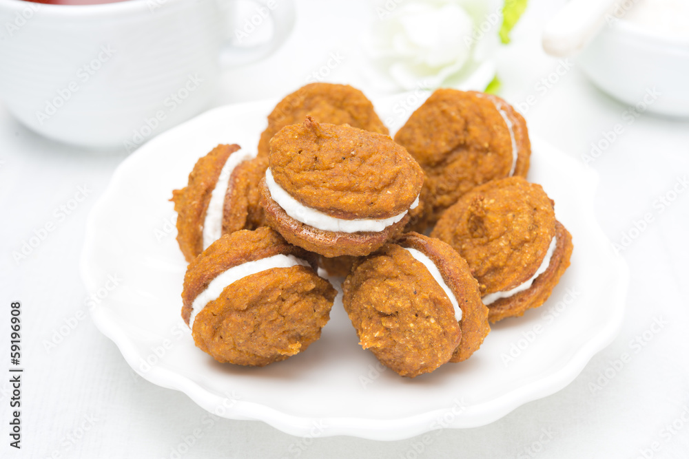 Pumpkin cookies with cream filling on a white plate Pumpkin cookies with cream filling on a white plate