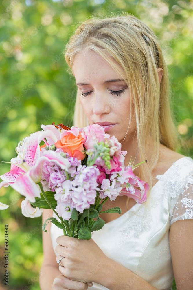 Blonde bride smelling her colourful bouquet Blonde bride smelling her colourful bouquet