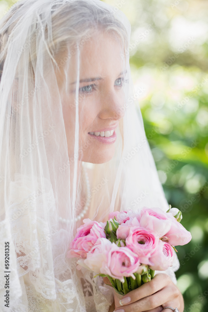 Happy bride wearing veil over face holding rose bouquet Happy bride wearing veil over face holding rose bouquet