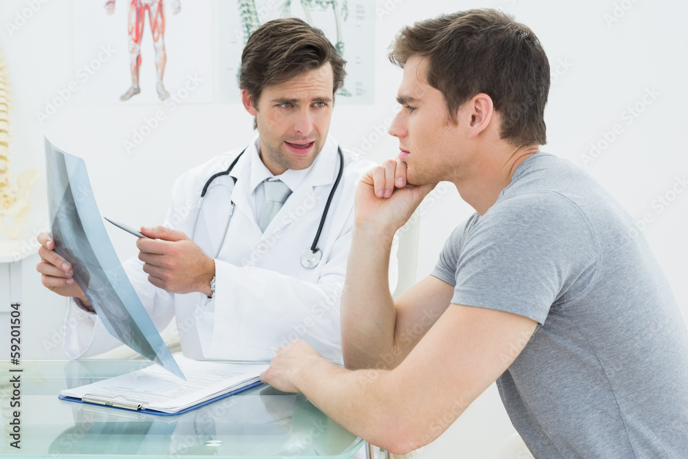 Obraz premium Male doctor explaining spine x-ray to patient