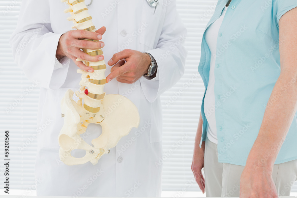 © lightwavemedia - Mid section of a doctor explaining the spine to patient