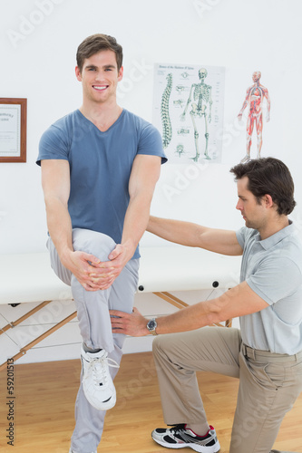Male therapist assisting a man with stretching exercises © lightwavemedia