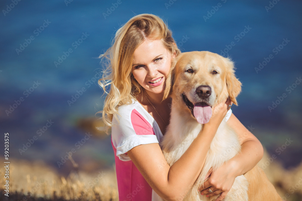 Beautiful woman with her dog playing on the sea shore. Outdoor p