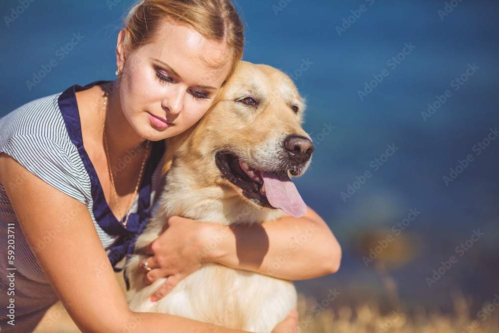 Beautiful woman with her dog playing on the sea shore. Outdoor p