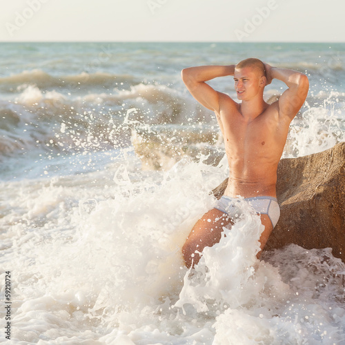 Young handsome muscular man walking out of the water