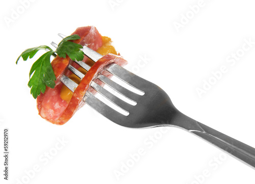 Piece of sausage with greens and mustard on a fork