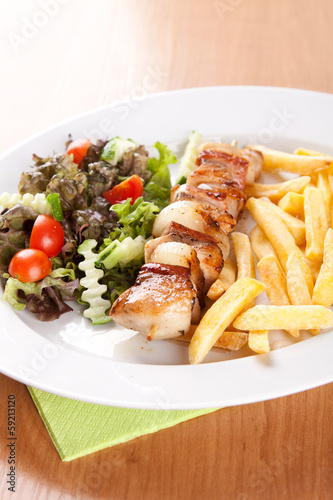 Fishing skewer with fries and vegetables