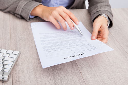 Businesswoman At Desk Holding Contract Paper