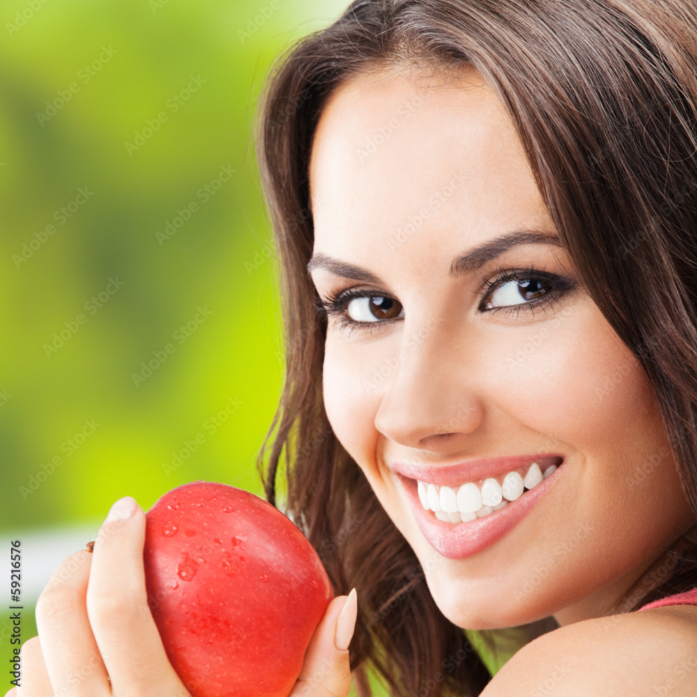 Young woman with red apple, outdoors