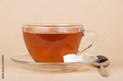 Transparent cup with tea, saucer and spoon