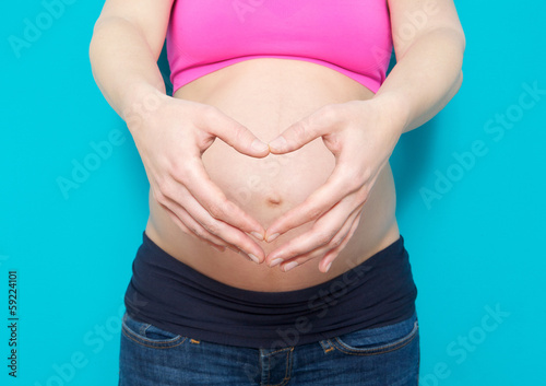 Pregnant young woman showing heart shape with hands