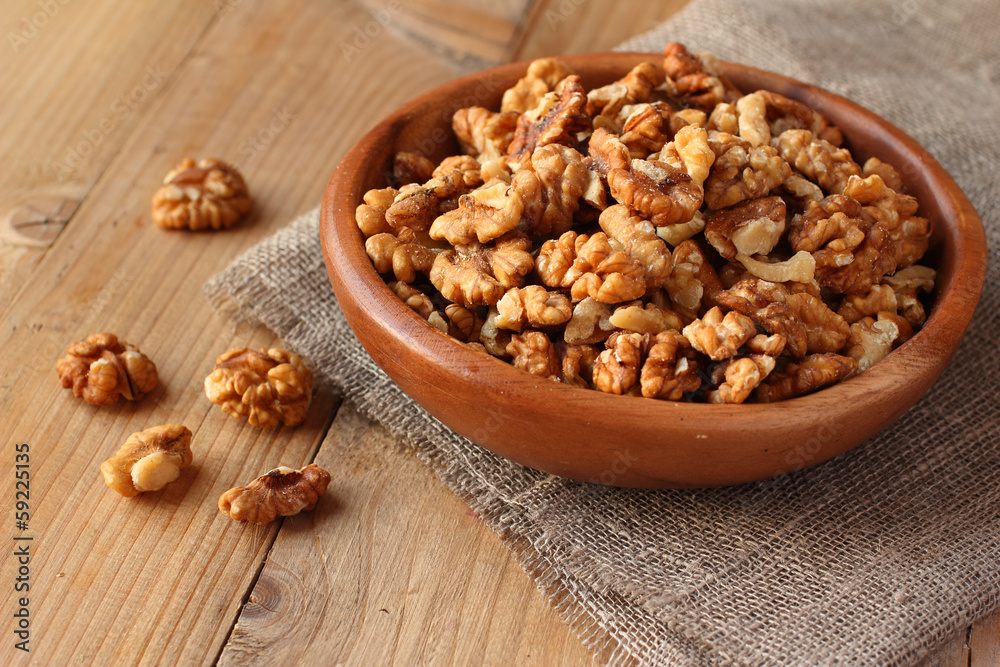 Fototapeta premium Shelled walnuts on wooden background with linen fabric