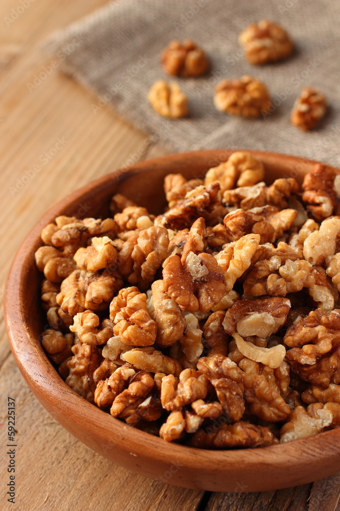 Shelled walnuts in wooden bowl on wooden background Shelled walnuts in wooden bowl on wooden background