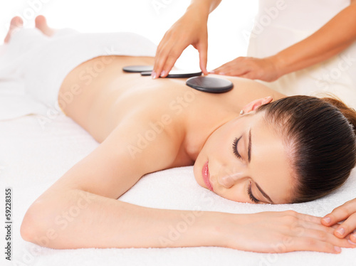 Woman having hot stone massage in spa salon.