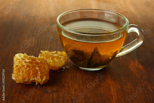 Transparent cup of green tea with honey on wooden background